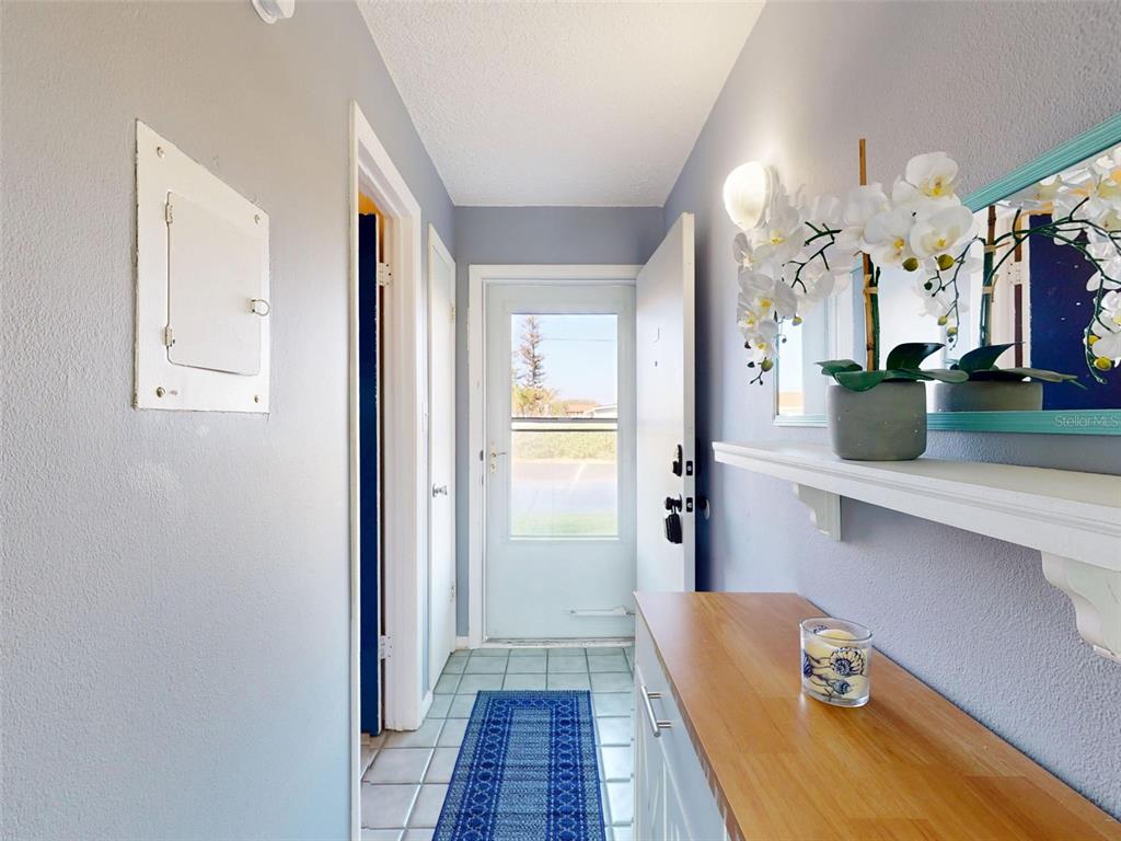 A hallway with light blue walls, tile flooring, a console table, and a mirror — 3700 S ATLANTIC AVENUE UNIT 103, NEW SMYRNA BEACH, FL