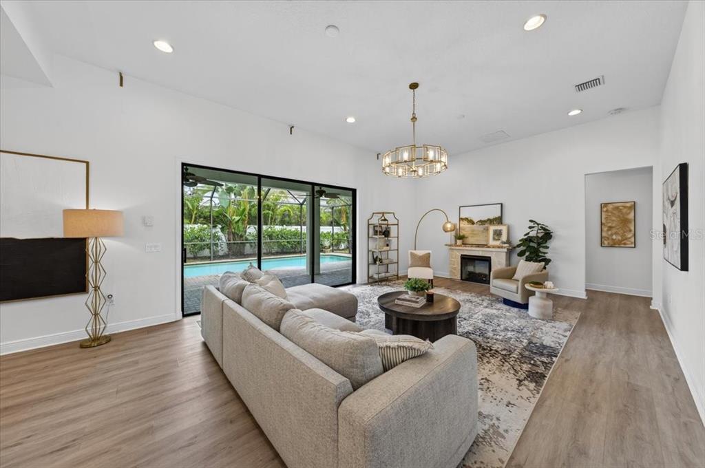 A living room features a grey sectional sofa, a fireplace, and sliding doors to a pool — 13008 EAGLES ENTRY DRIVE, ODESSA, FL