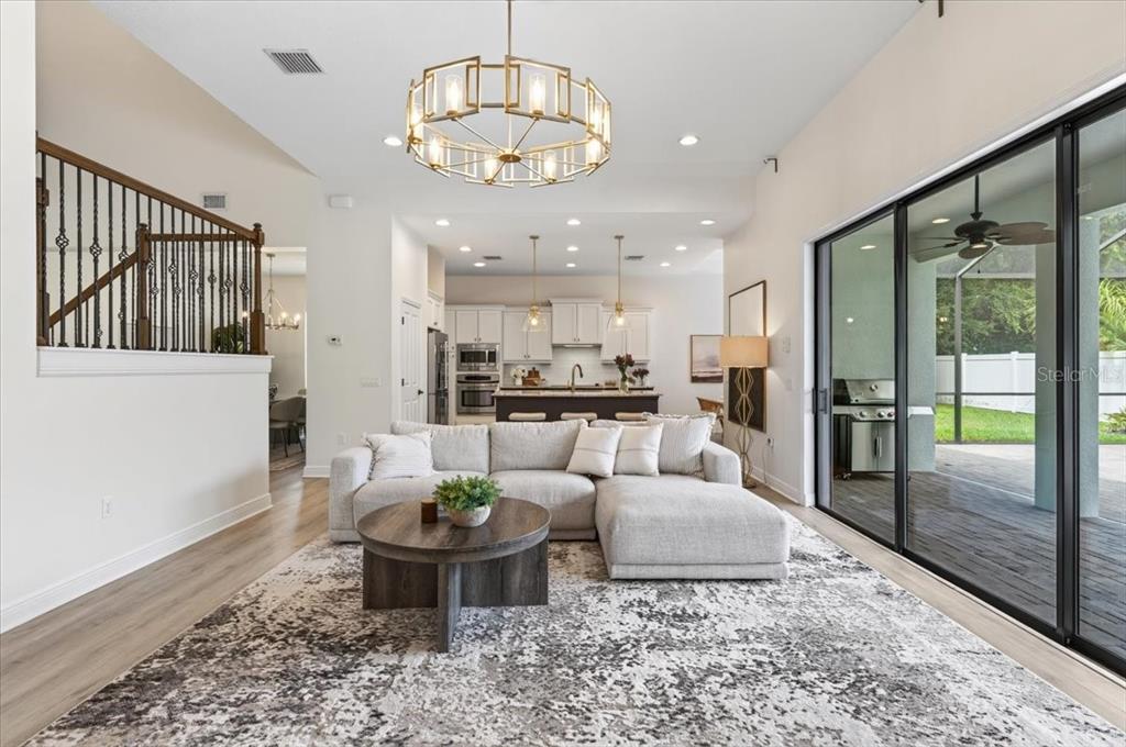 A living room with a sectional sofa and coffee table opens to a kitchen area — 13008 EAGLES ENTRY DRIVE, ODESSA, FL