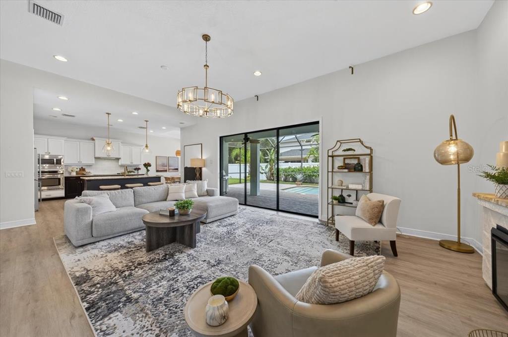 A modern living room with a sectional sofa, area rug, and sliding doors to a pool — 13008 EAGLES ENTRY DRIVE, ODESSA, FL