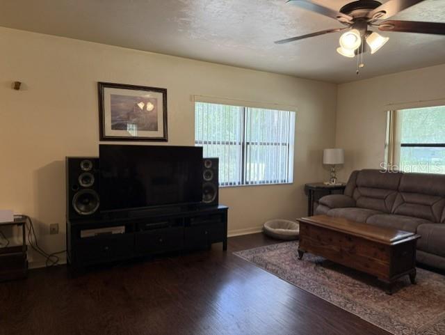 A living room features dark wood flooring, a television console with speakers, and a sofa — 14236 SW 76TH WAY, LAKE BUTLER, FL