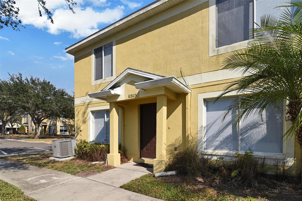 A two-story yellow stucco building features a covered entryway with a brown door — 10805 KEYS GATE DRIVE, RIVERVIEW, FL