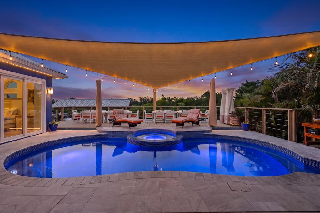 A swimming pool and hot tub sit on a patio beneath a large shade sail — 704 EAGLE LANE, APOLLO BEACH, FL
