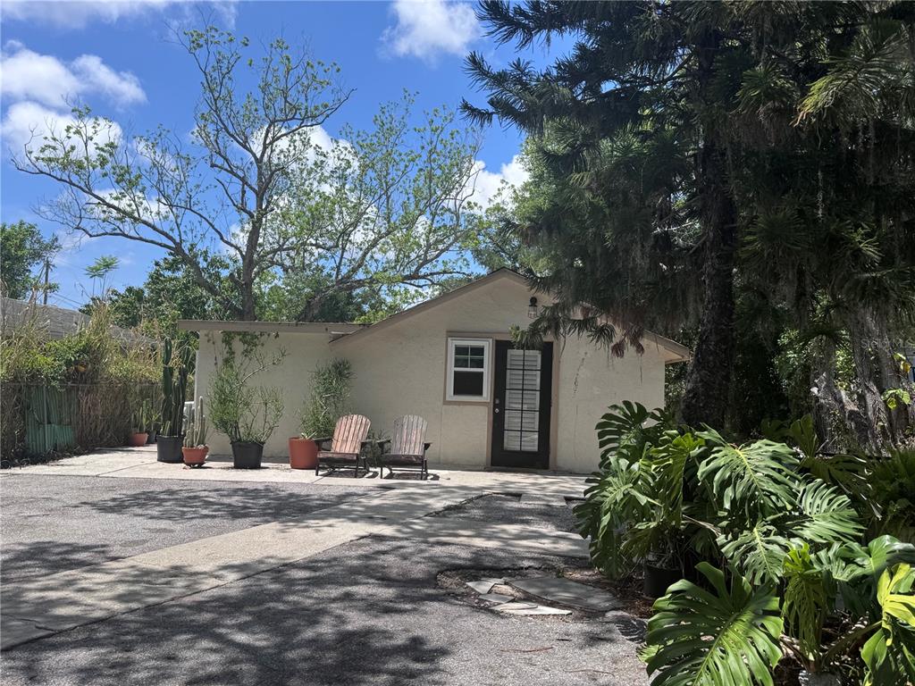 A small, light-colored house with a dark door and two chairs sits in a yard — 3520 19TH STREET E, BRADENTON, FL