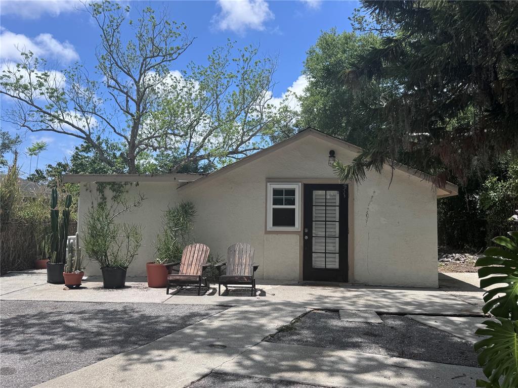 A small, light-colored stucco cottage features a dark-framed glass door, a window, and two chairs — 3520 19TH STREET E, BRADENTON, FL