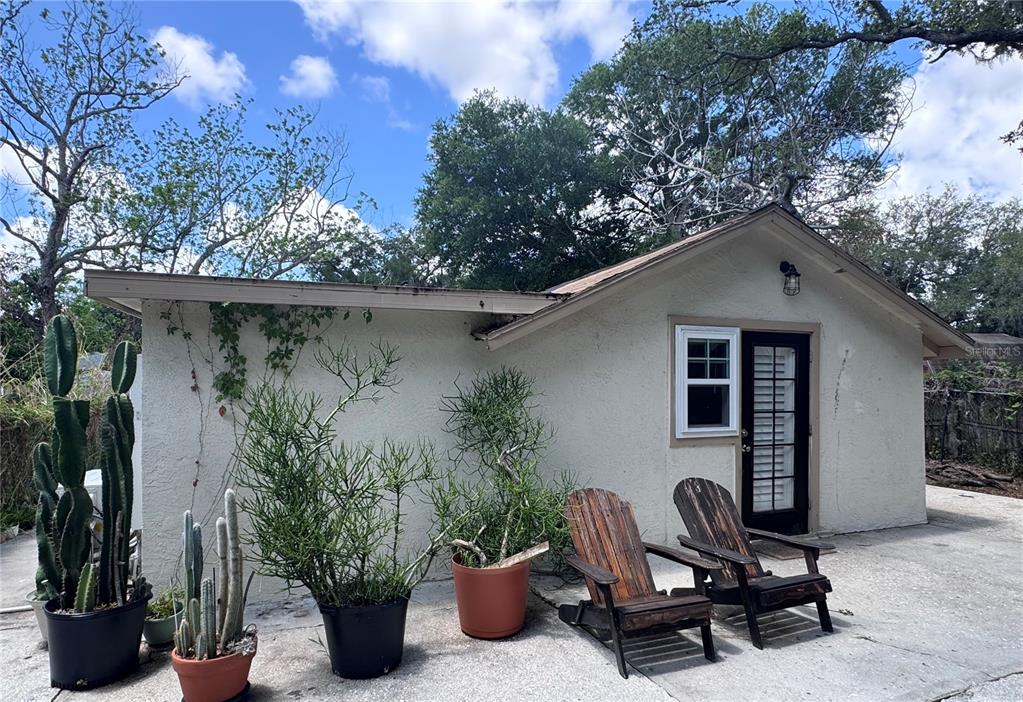 The exterior of a small, stucco-walled building features a patio with potted cacti and chairs — 3520 19TH STREET E, BRADENTON, FL