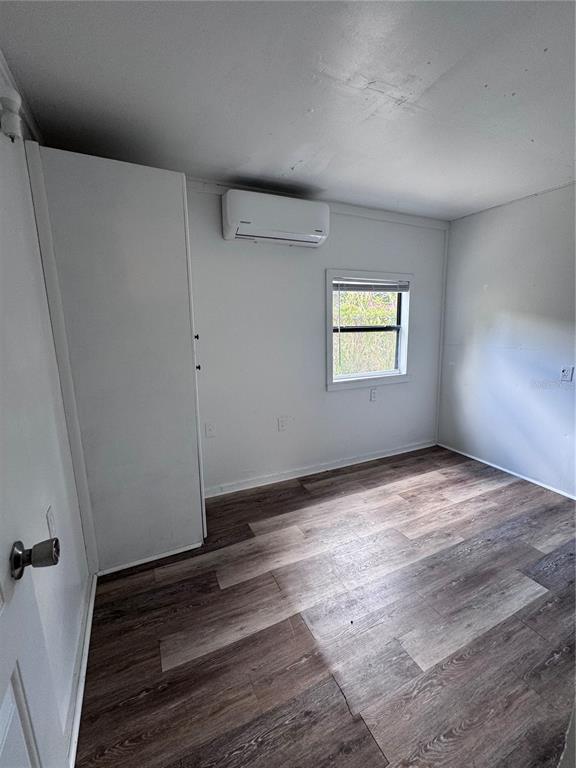 A small room with wood-look flooring, a window, and a wall-mounted air conditioning unit — 3520 19TH STREET E, BRADENTON, FL