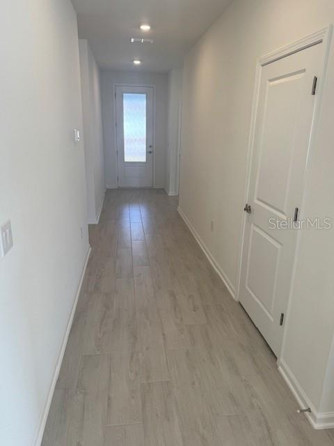 A hallway with light wood-look tile flooring leads to an exterior door with a glass panel — 144 CEDAR KNOLL CIRCLE, ST AUGUSTINE, FL