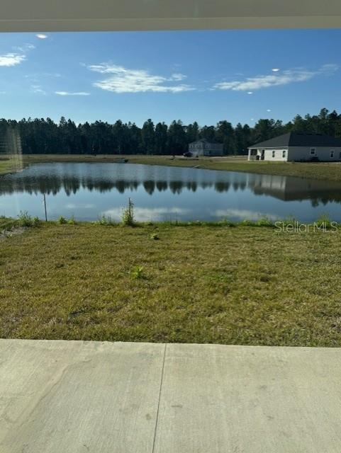 A concrete patio overlooks a grassy yard, a pond, and distant houses under a blue sky — 144 CEDAR KNOLL CIRCLE, ST AUGUSTINE, FL