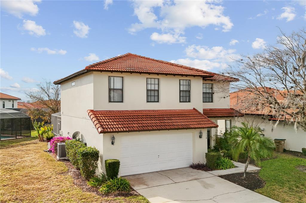 A two-story house with a white stucco exterior, red tile roof, and a two-car garage — 114 SUMMER PLACE LOOP, CLERMONT, FL