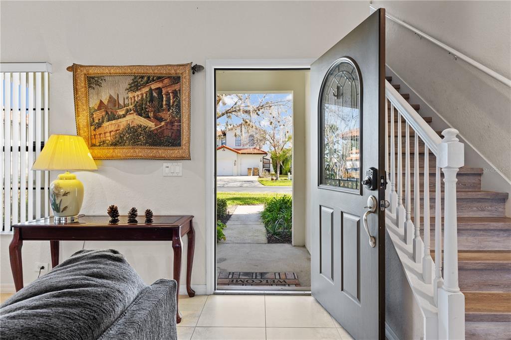 An entryway features a dark front door, a staircase with wood steps, and a console table — 114 SUMMER PLACE LOOP, CLERMONT, FL