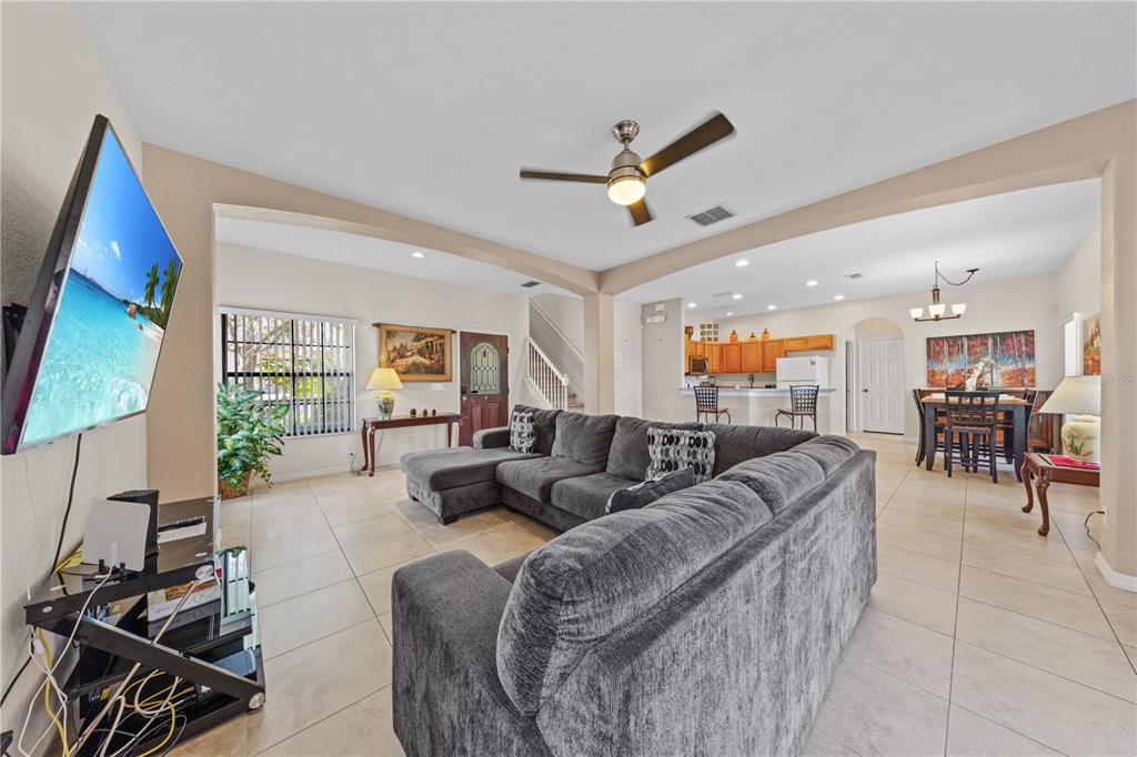 A living room with tile floors, a large gray sectional sofa, and an open kitchen — 114 SUMMER PLACE LOOP, CLERMONT, FL