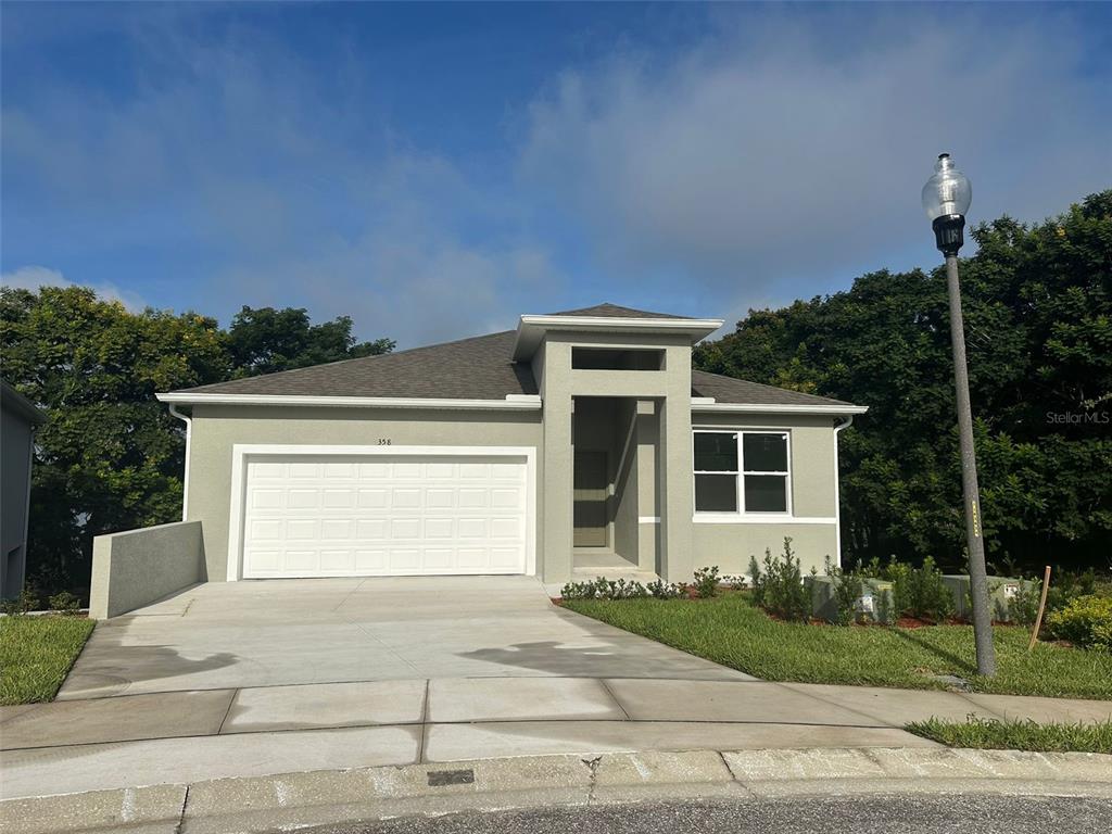 A single-story house with a two-car garage, light-colored stucco exterior, and a front entryway — 358 CHEROKEE AVENUE, HAINES CITY, FL