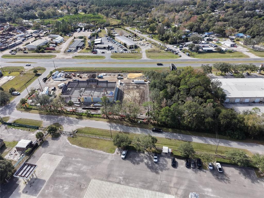 An aerial view shows a construction site with a steel frame building and parking lots — E COLONIAL DR, ORLANDO, FL