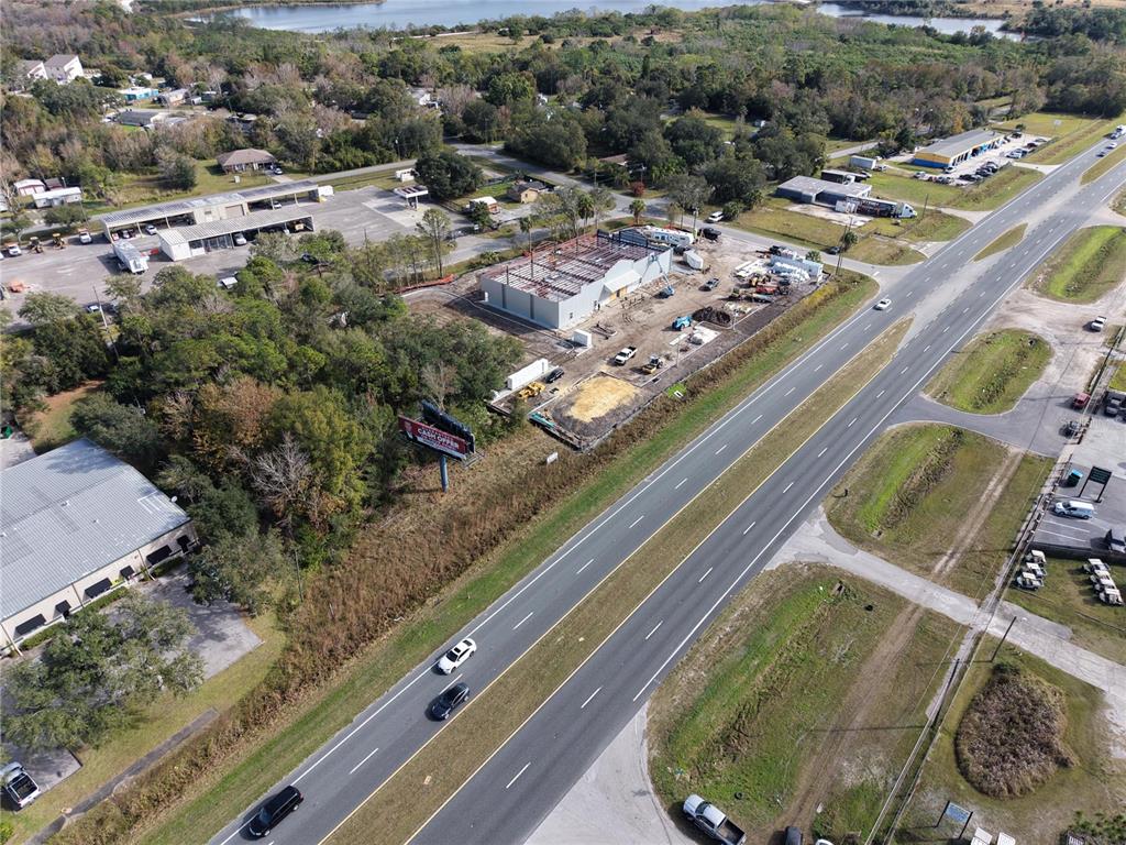 An aerial view shows a construction site with a building frame next to a highway — E COLONIAL DR, ORLANDO, FL