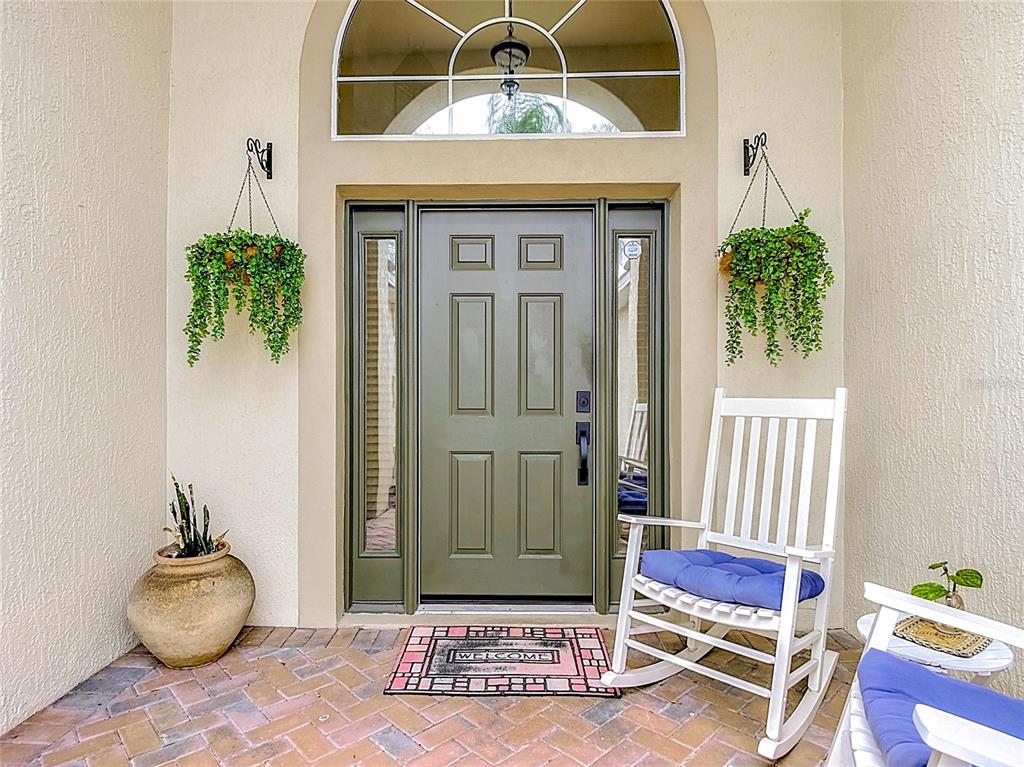 A front entryway features a green door, a white rocking chair, and two hanging plants — 335 REGENCY STREET, DAVENPORT, FL