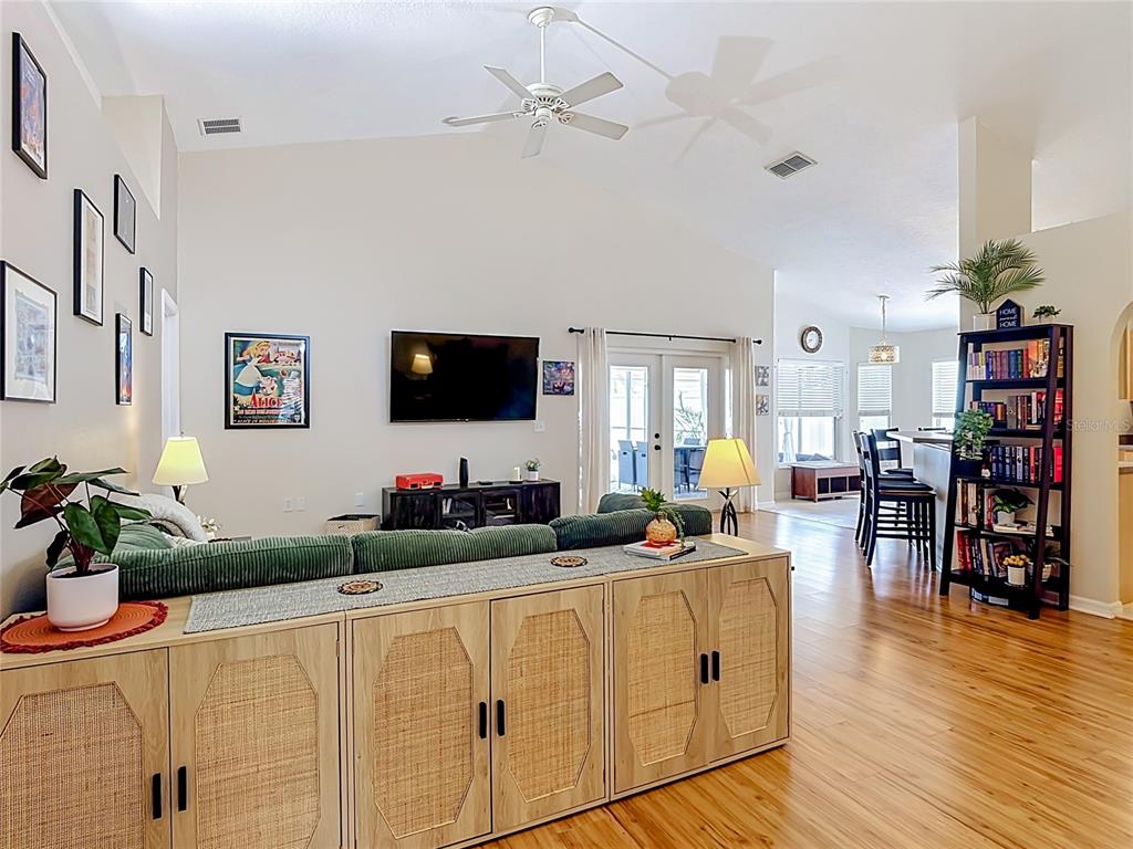 A living room features a green sectional sofa, a rattan console, and a wall-mounted television — 335 REGENCY STREET, DAVENPORT, FL