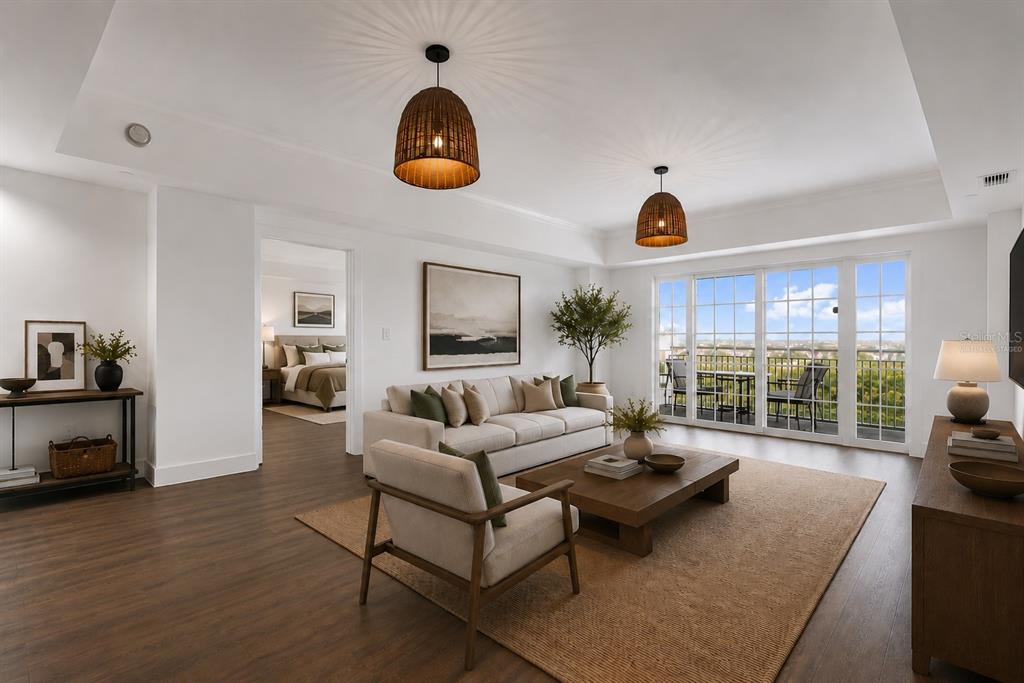 A living room with a beige sofa, wooden coffee table, and balcony access — 7593 GATHERING DRIVE UNIT 707, REUNION, FL