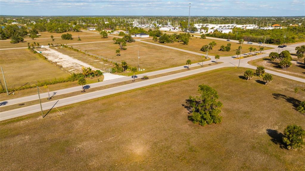 An aerial view shows a large, undeveloped grassy lot next to a paved road — 99 HARNESS ROAD, PLACIDA, FL