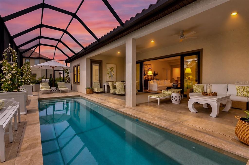 A covered patio features a rectangular swimming pool, outdoor seating, and a view of the sunset — 8818 EASTWYCK DRIVE, PARRISH, FL