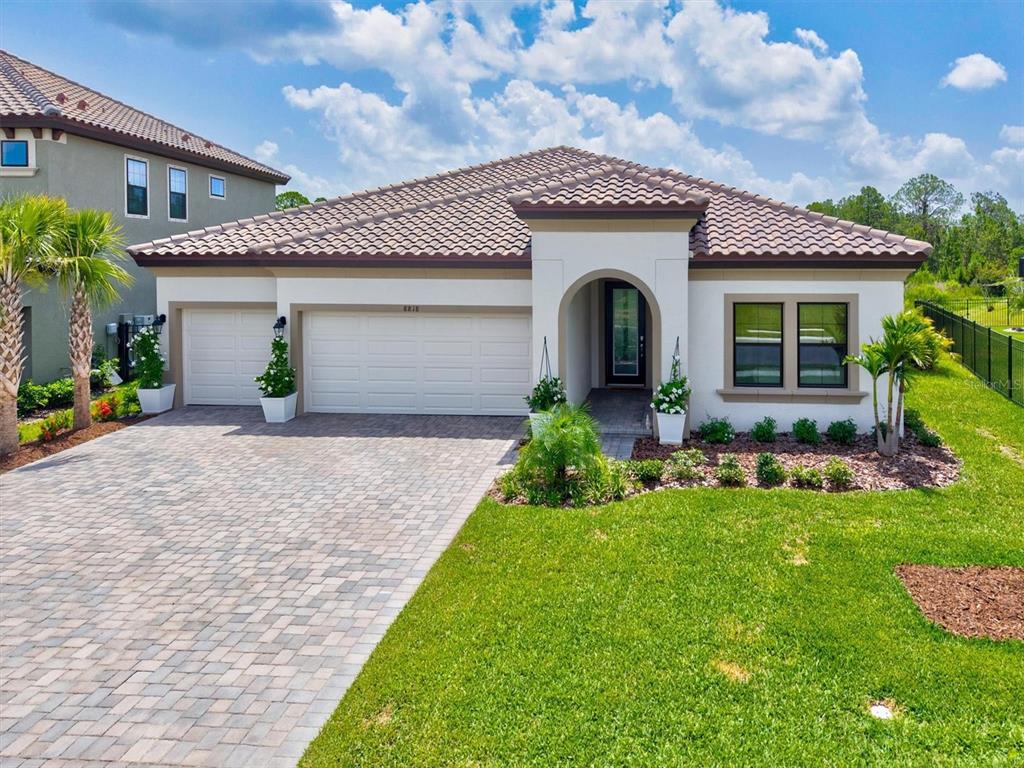 A single-story house with a tiled roof, three-car garage, and a paved driveway — 8818 EASTWYCK DRIVE, PARRISH, FL