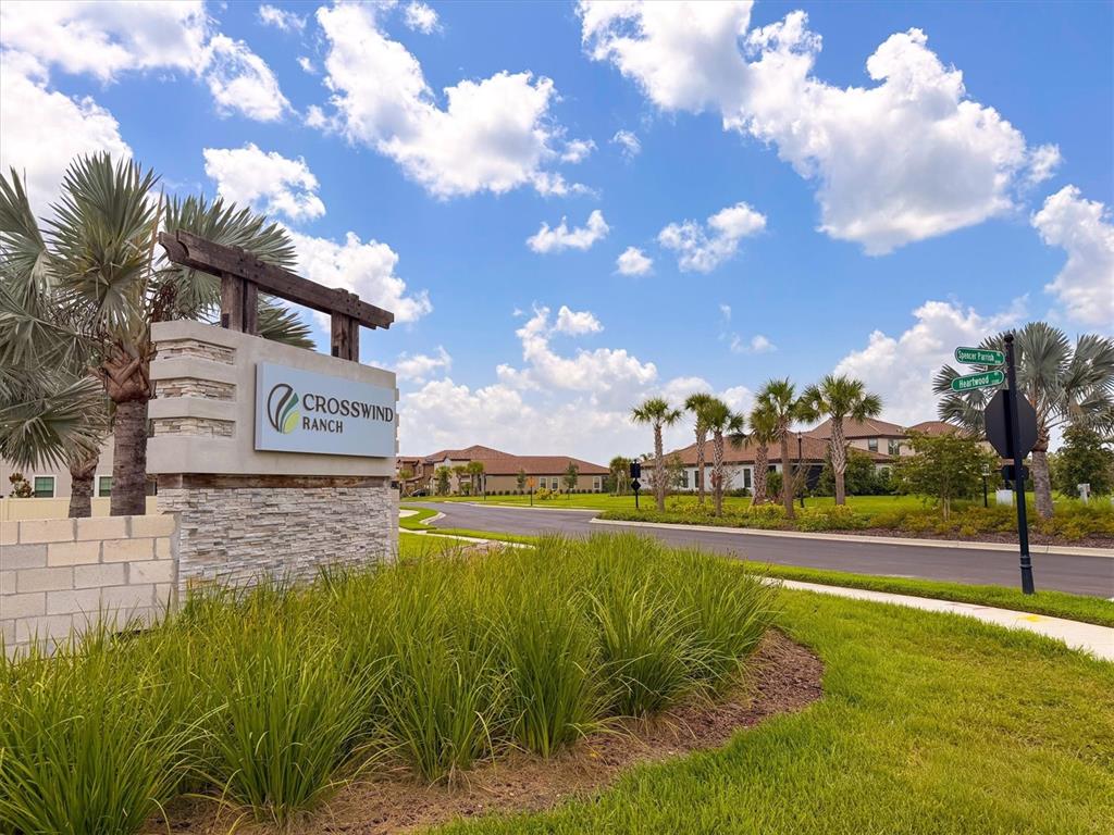 A stone monument sign for Crosswind Ranch stands beside a paved road with palm trees — 8818 EASTWYCK DRIVE, PARRISH, FL