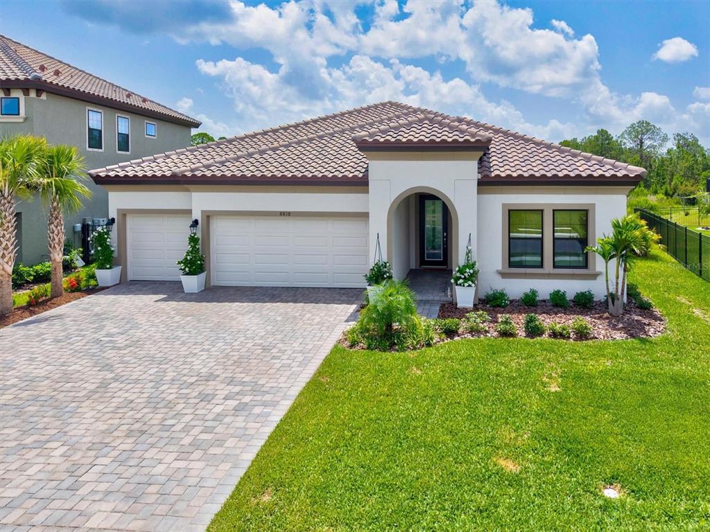 A single-story house with a tiled roof, a three-car garage, and a paved driveway — 8818 EASTWYCK DRIVE, PARRISH, FL