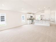 An open-concept living room flows into a kitchen with white cabinets and a center island — 193 CONCH DRIVE, KISSIMMEE, FL
