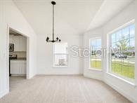 A bright dining area features neutral carpeting, a modern chandelier, and large windows — 193 CONCH DRIVE, KISSIMMEE, FL