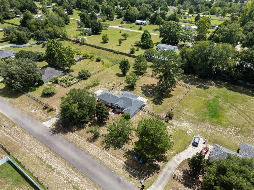 An aerial view shows a single-story house with a fenced yard and a paved driveway — 9445 SW 96TH TERRACE, GAINESVILLE, FL