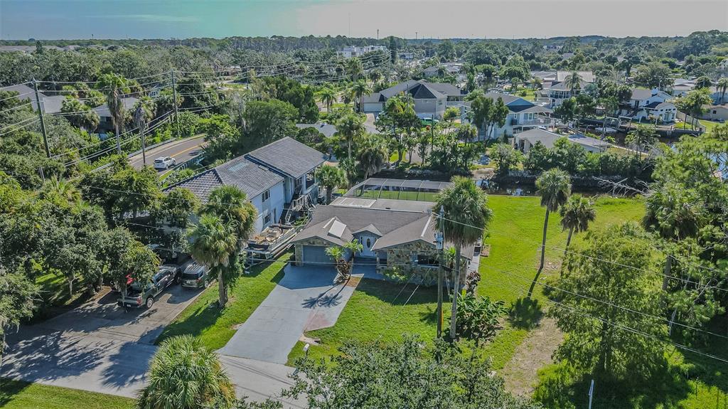 An aerial view of a single-story house with a pool cage and adjacent multi-story building — 5254 MILLER BAYOU DRIVE, PORT RICHEY, FL