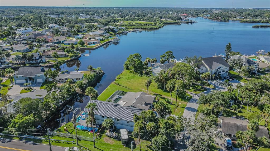 An aerial view shows a waterfront house with a pool and dock along a canal — 5254 MILLER BAYOU DRIVE, PORT RICHEY, FL