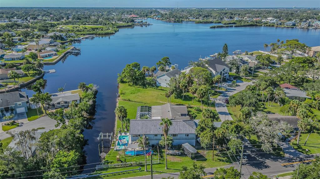 An aerial view of a waterfront house with a pool, dock, and surrounding residential neighborhood — 5254 MILLER BAYOU DRIVE, PORT RICHEY, FL