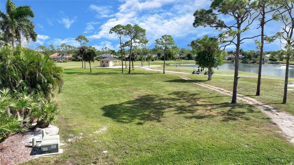 A grassy yard overlooks a golf course with a pond, trees, and a small structure — 3000 BIG BEND CIRCLE, PUNTA GORDA, FL