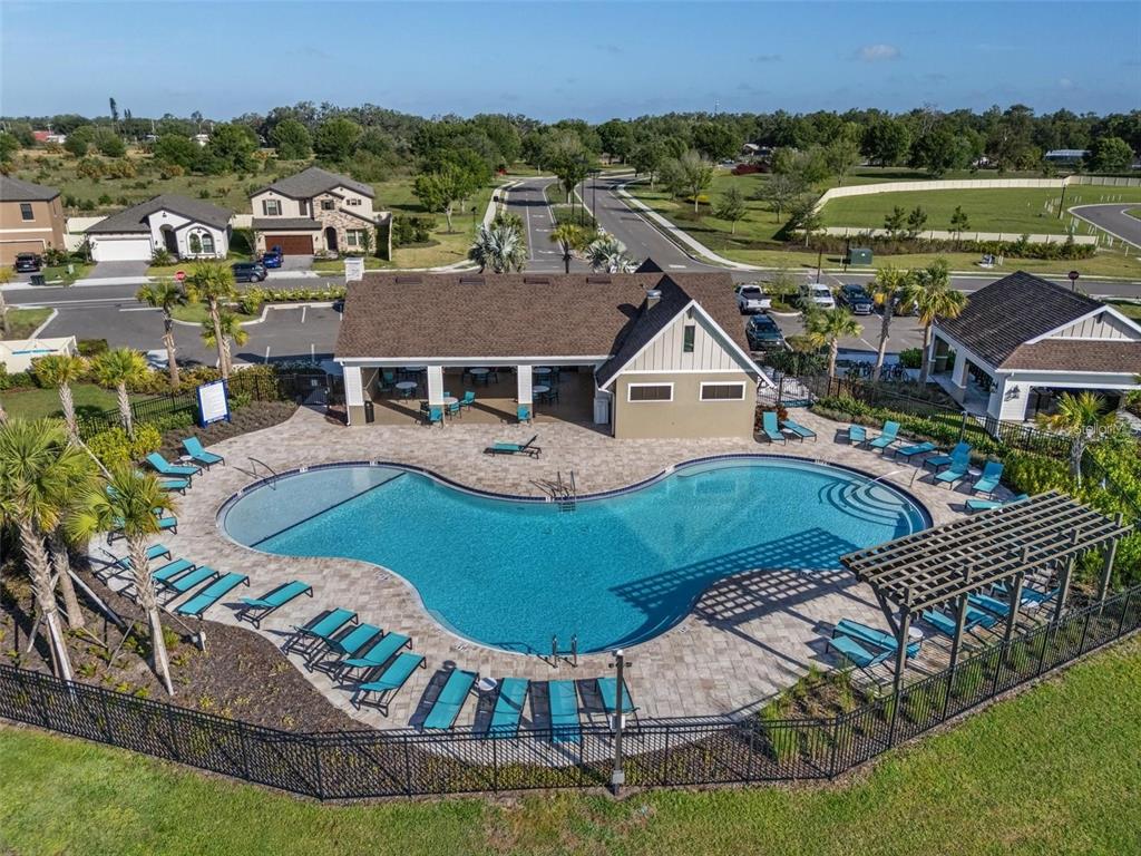 An aerial view of a community swimming pool with lounge chairs and a clubhouse building — 13029 OAK HILL WAY, PARRISH, FL