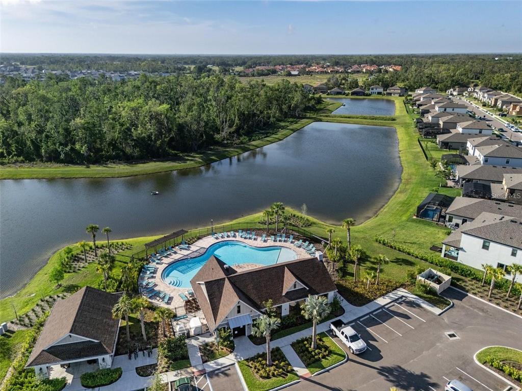 An aerial view shows a community swimming pool, clubhouse, parking lot, and adjacent ponds — 13029 OAK HILL WAY, PARRISH, FL