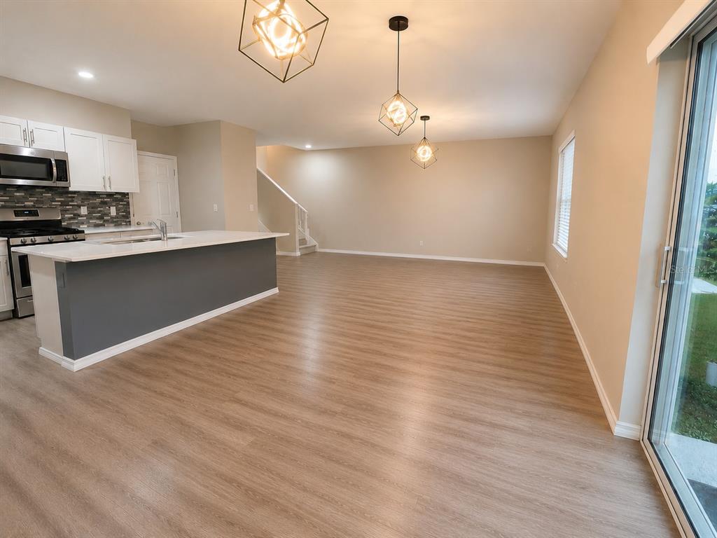 An open-concept kitchen with a gray island and white cabinets flows into a living area — 13029 OAK HILL WAY, PARRISH, FL