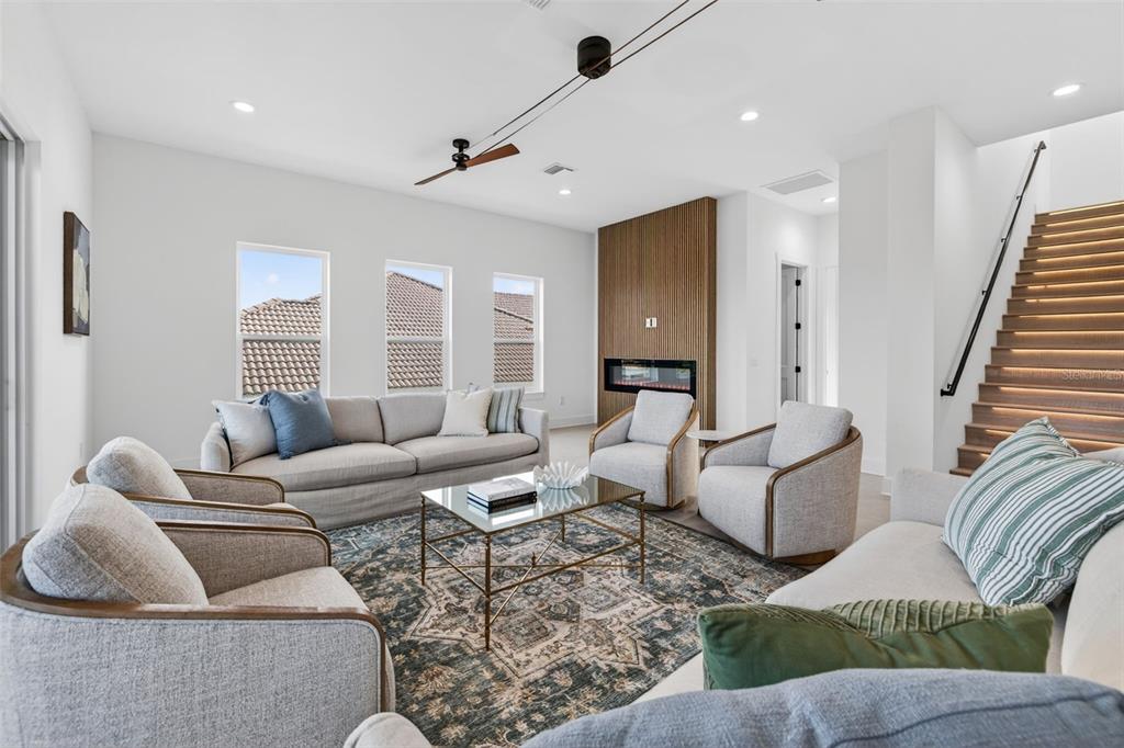 A living room features light-colored furniture, a glass coffee table, and wood-slatted accent walls — 3221 GULF BOULEVARD, BELLEAIR BEACH, FL