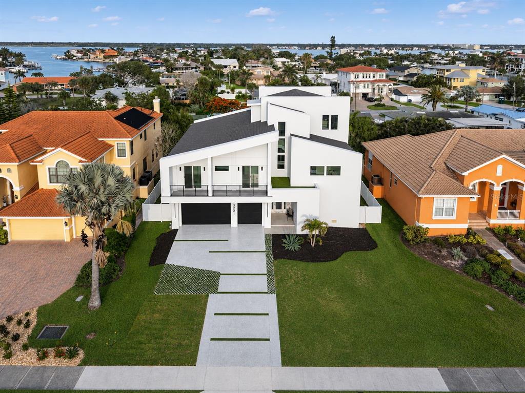 A modern two-story white house features a two-car garage and a paved driveway with grass — 3221 GULF BOULEVARD, BELLEAIR BEACH, FL