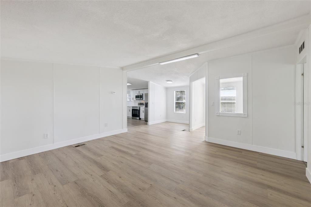 An interior view of a living area with light wood flooring and white paneled walls — 5038 CAMBRIDGE DRIVE, MIMS, FL