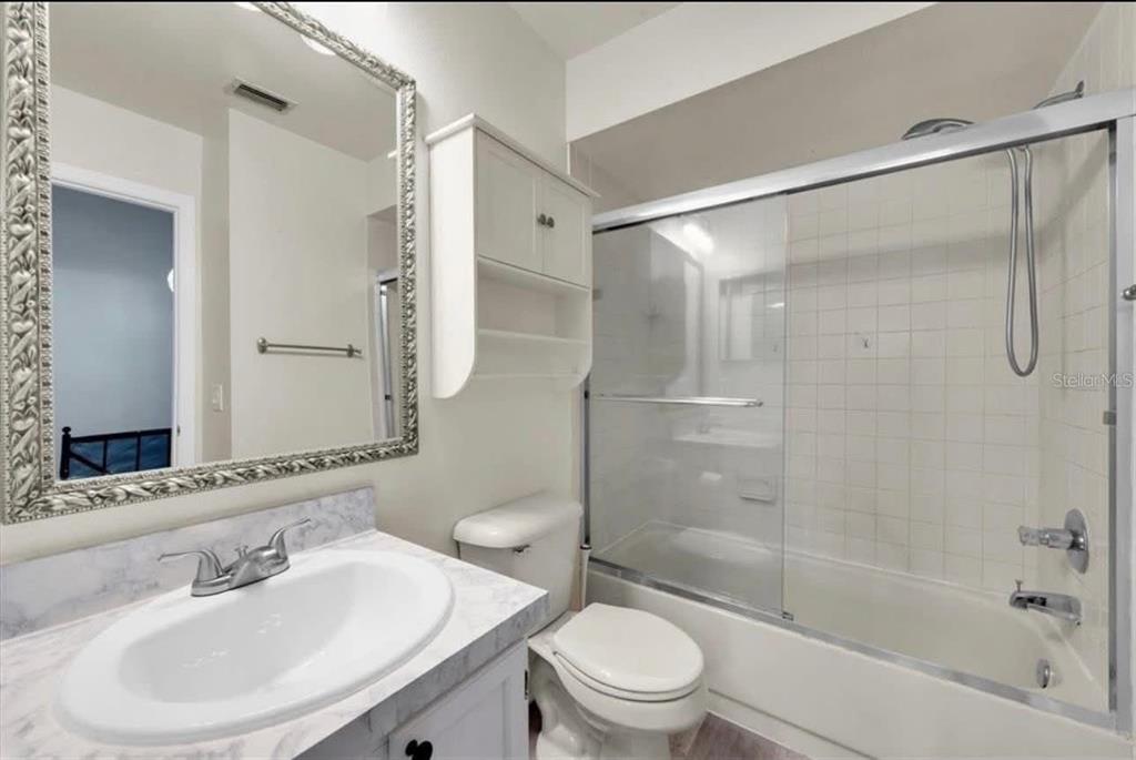 A bathroom features a vanity with a marble-look countertop, a toilet, and a shower-tub combo — 11338 STRATTON PARK DRIVE, TEMPLE TERRACE, FL