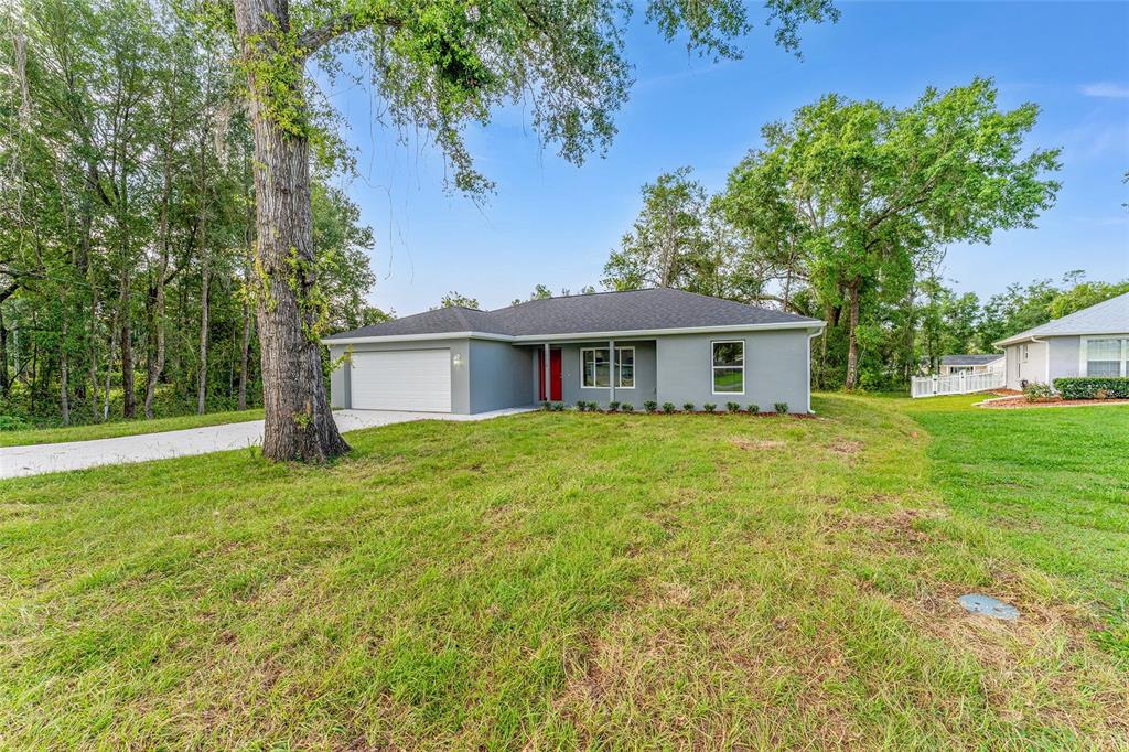 A gray single-story house with a white garage door and a red front door — 13119 NE 7TH LOOP, SILVER SPRINGS, FL