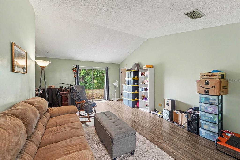 A covered patio features gray flooring, blue walls, a ceiling light, and sliding glass doors — 9074 HEATHER BOULEVARD, WEEKI WACHEE, FL