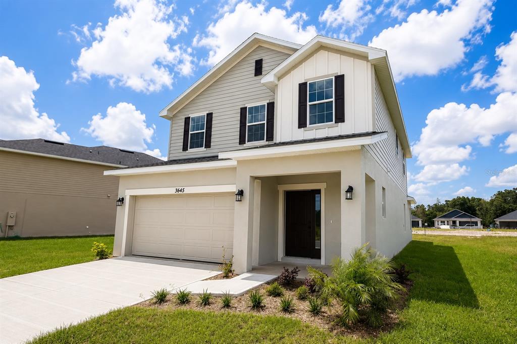 A two-story house with a beige stucco exterior, a garage, and a front entrance — 3645 BRIARLYNNE WAY, ST CLOUD, FL