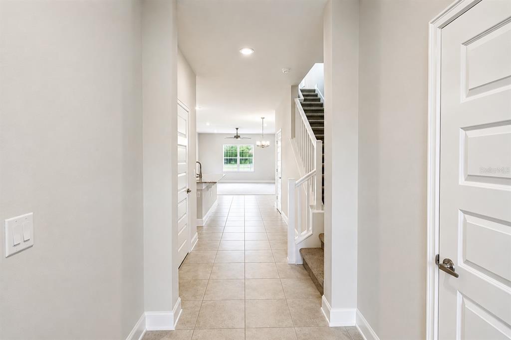 A tiled entryway leads to a living area with a staircase and white doors — 3645 BRIARLYNNE WAY, ST CLOUD, FL