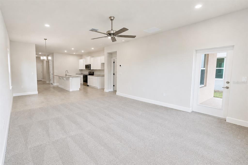 A kitchen features white cabinets, granite countertops, a center island, and stainless steel appliances — 3645 BRIARLYNNE WAY, ST CLOUD, FL