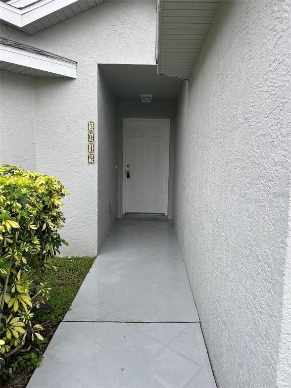 A white front door is recessed within a covered entryway featuring a gray painted walkway — 3049 SE 38TH AVENUE, OKEECHOBEE, FL