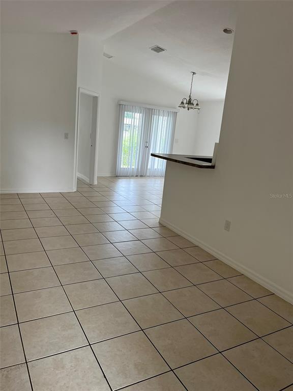 A tiled room features a breakfast bar, a doorway, and glass doors leading outside — 3049 SE 38TH AVENUE, OKEECHOBEE, FL