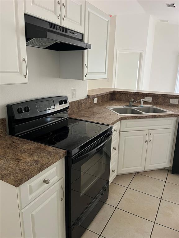 A kitchen features white cabinets, a black stove, and a brown laminate countertop — 3049 SE 38TH AVENUE, OKEECHOBEE, FL