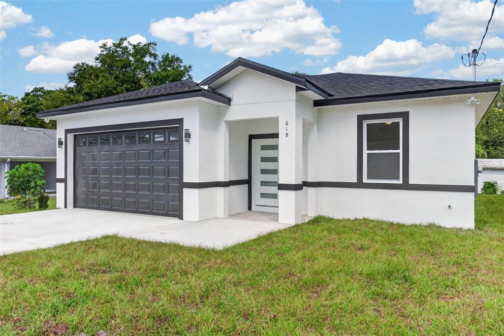 A single-story house with white stucco walls, dark trim, a garage, and a front entrance — 619 W VALENCIA STREET, LAKELAND, FL